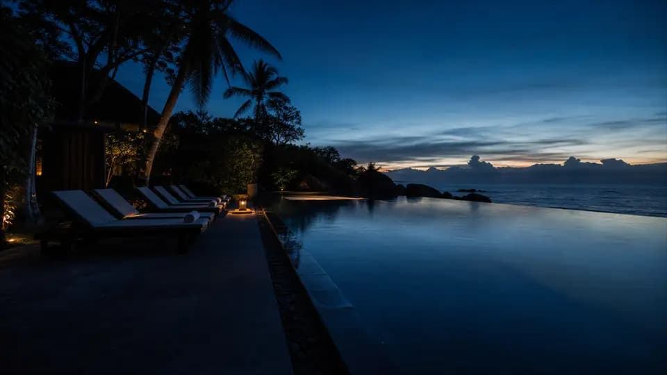 Piscine à débordement d'un resort face à la mer au crépuscule